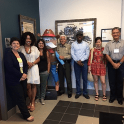 A group of people standing in front of a painting.