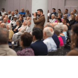 A man is speaking to an audience in front of many people.