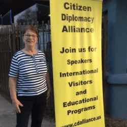 A woman standing next to a yellow banner.