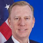 A man in suit and tie next to an american flag.