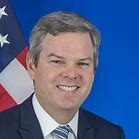 A man in suit and tie next to an american flag.