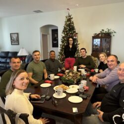 Group gathered around table near Christmas tree.