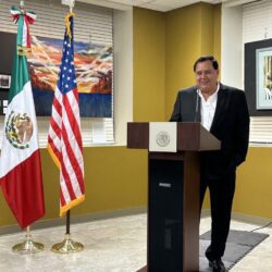 Man speaking at podium with two flags.