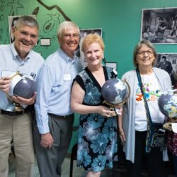 Group holding globes, smiling in classroom.
