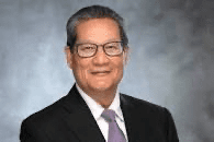 Man in suit and glasses, smiling confidently.