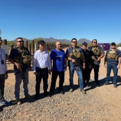 Group of people standing outdoors in sunlight.