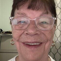 Smiling woman wearing glasses and earrings.