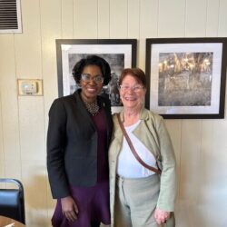 Two women smiling in front of paintings.